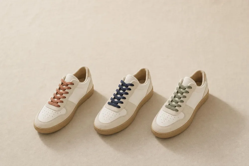 Three identical sneakers at a diagonal, only the laces in different muted colors.